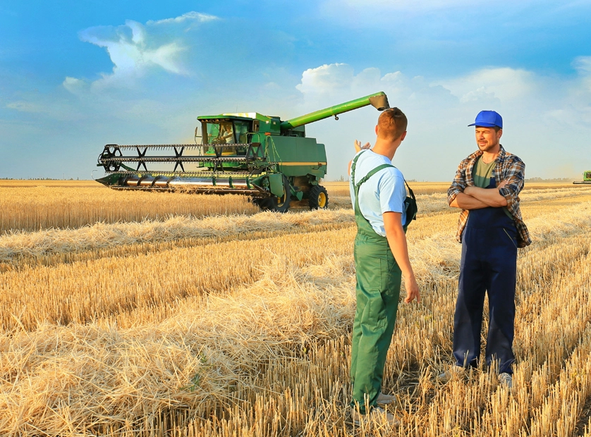 Zwei Menschen sprechen auf einem Feld vor einem Mähdrescher